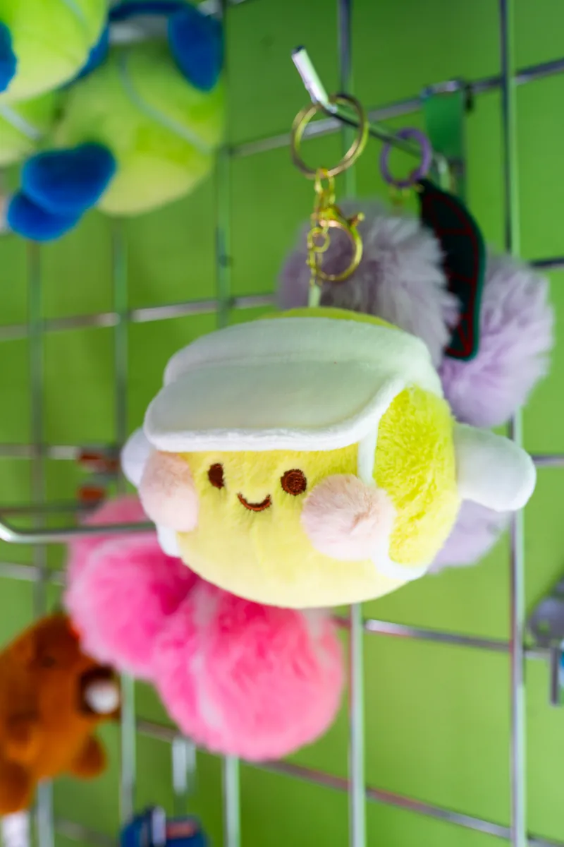 A plush tennis-ball keychain on the accessories wall