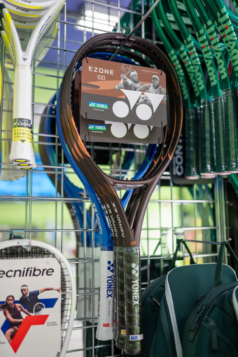 A Yonex Ezone 100 racquet on the wall at URacquet Shop