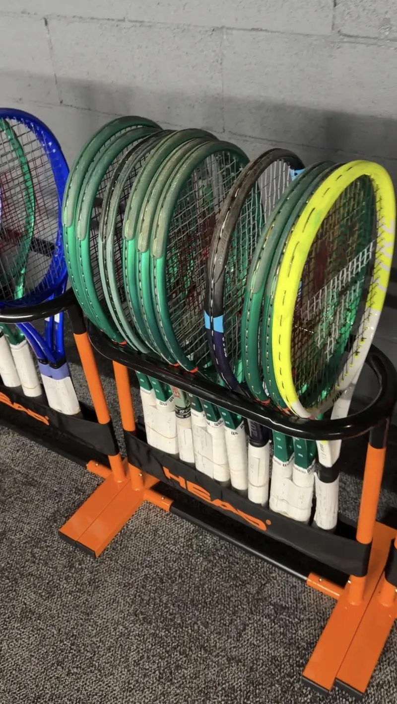 Players' racquets tagged and racked for pick-up in a tournament stringing room