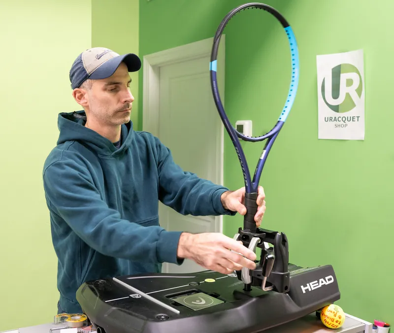 Mark Kuczynski placing a racquet on the Head diagnostic machine to measure its weight, balance and swing weight